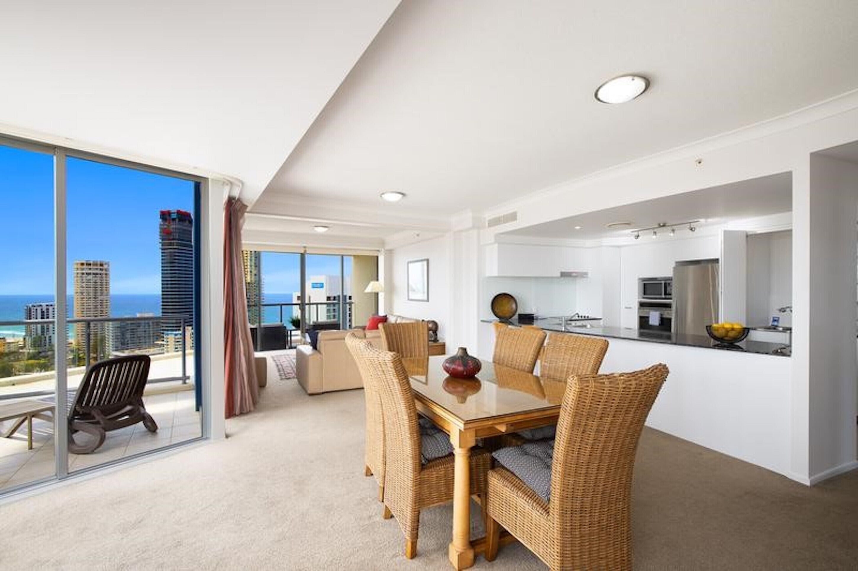 A modern apartment with a dining area, kitchen, and large balcony with a city view.