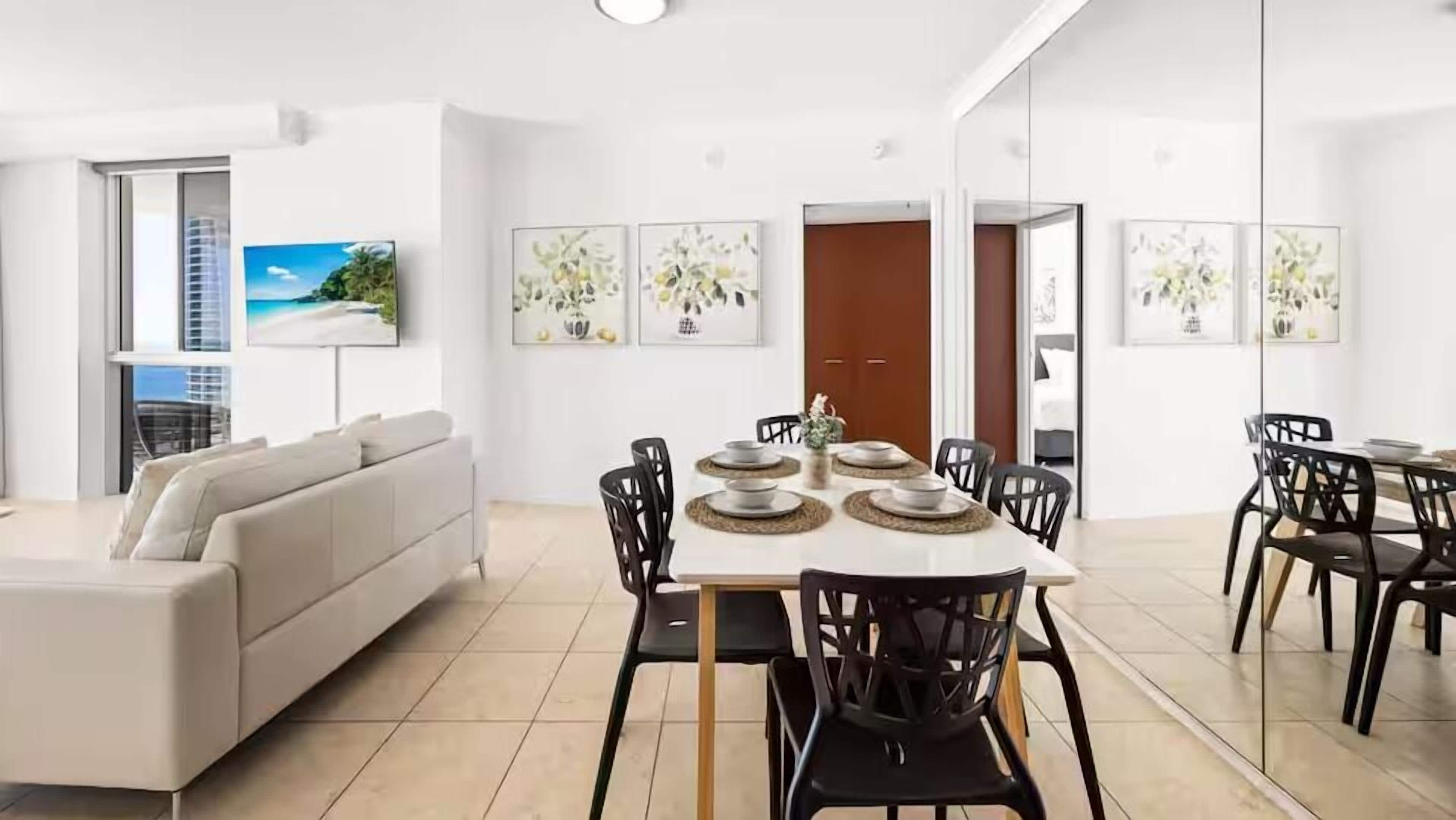 Una sala de estar moderna con un sofá, una mesa de comedor con platos y sillas.
