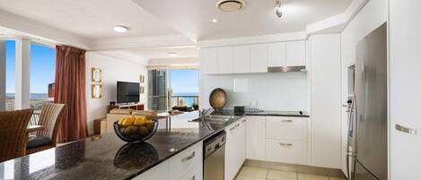 A modern kitchen with white cabinets, a granite countertop, and a stainless steel refrigerator.