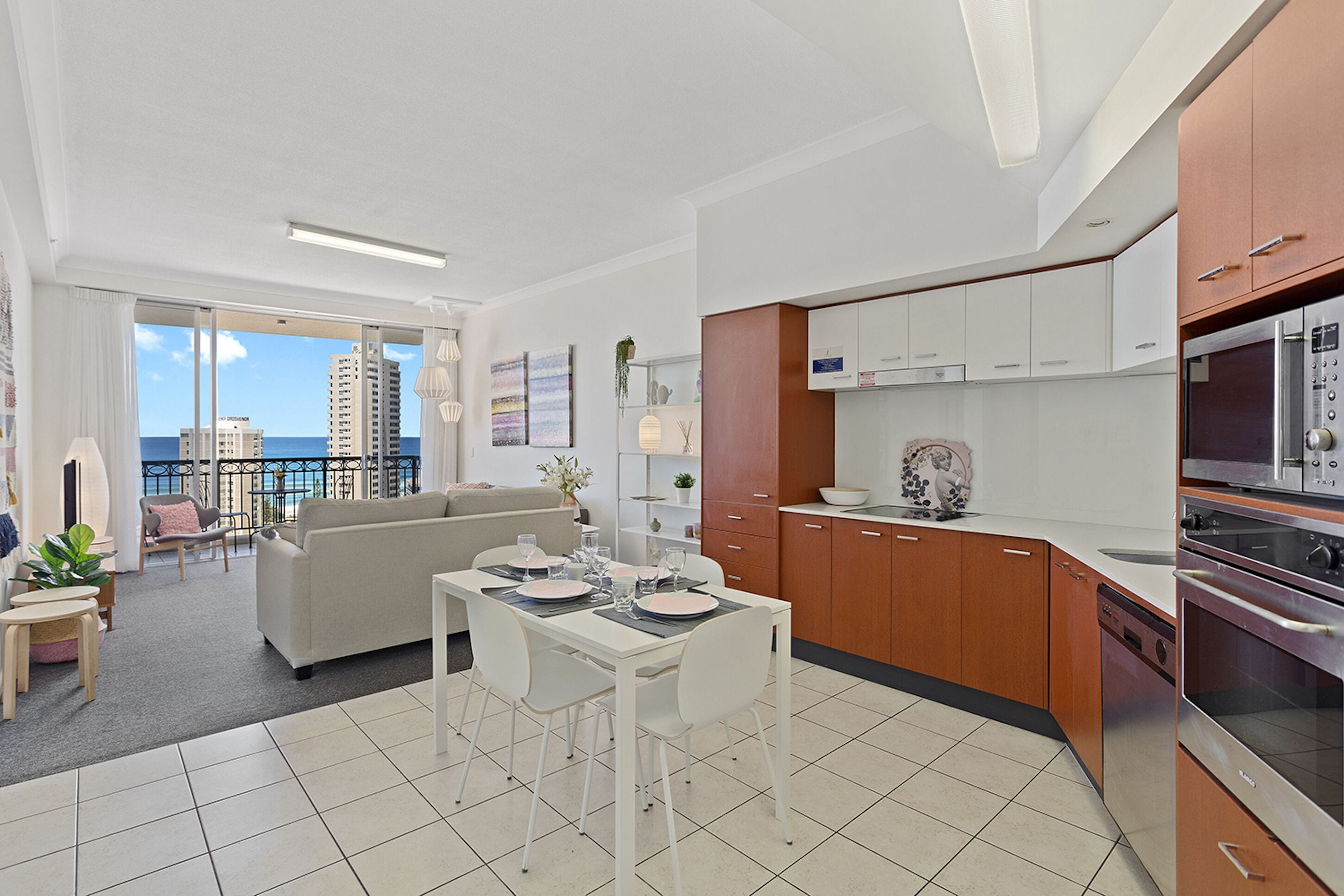 A modern apartment with a dining area, kitchen, and a balcony with a view of the sea.