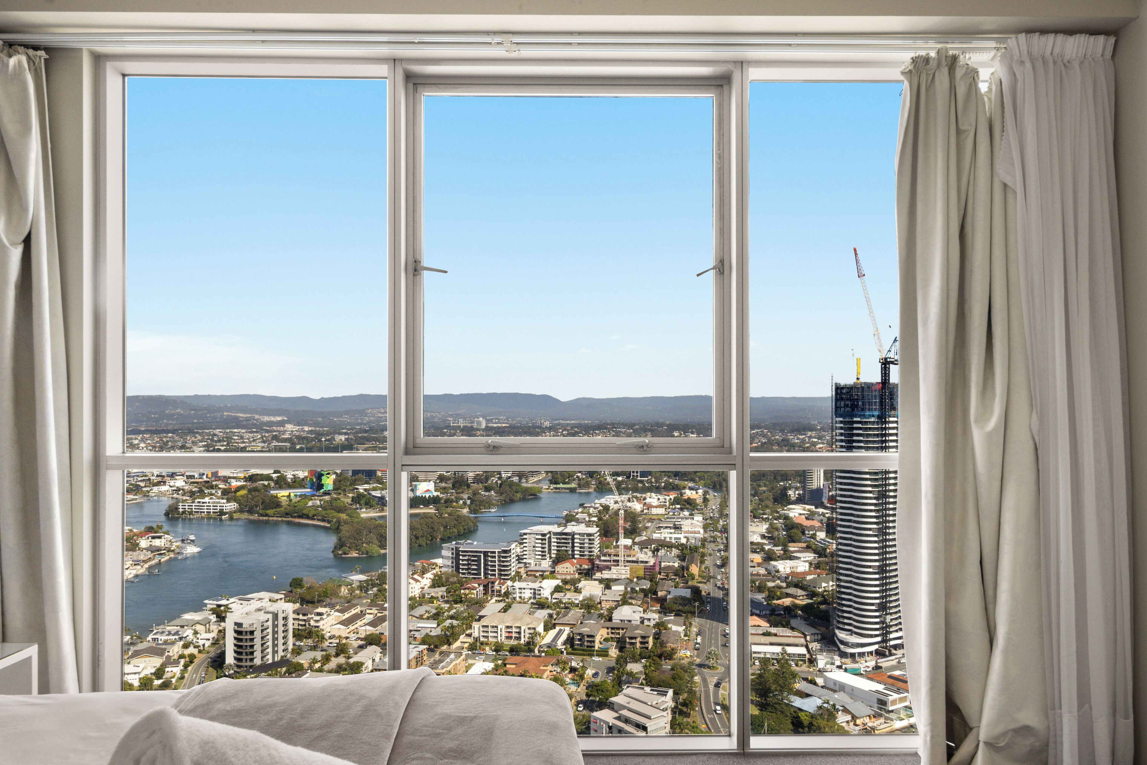A room with a large window offering a view of a cityscape, including a river and buildings.