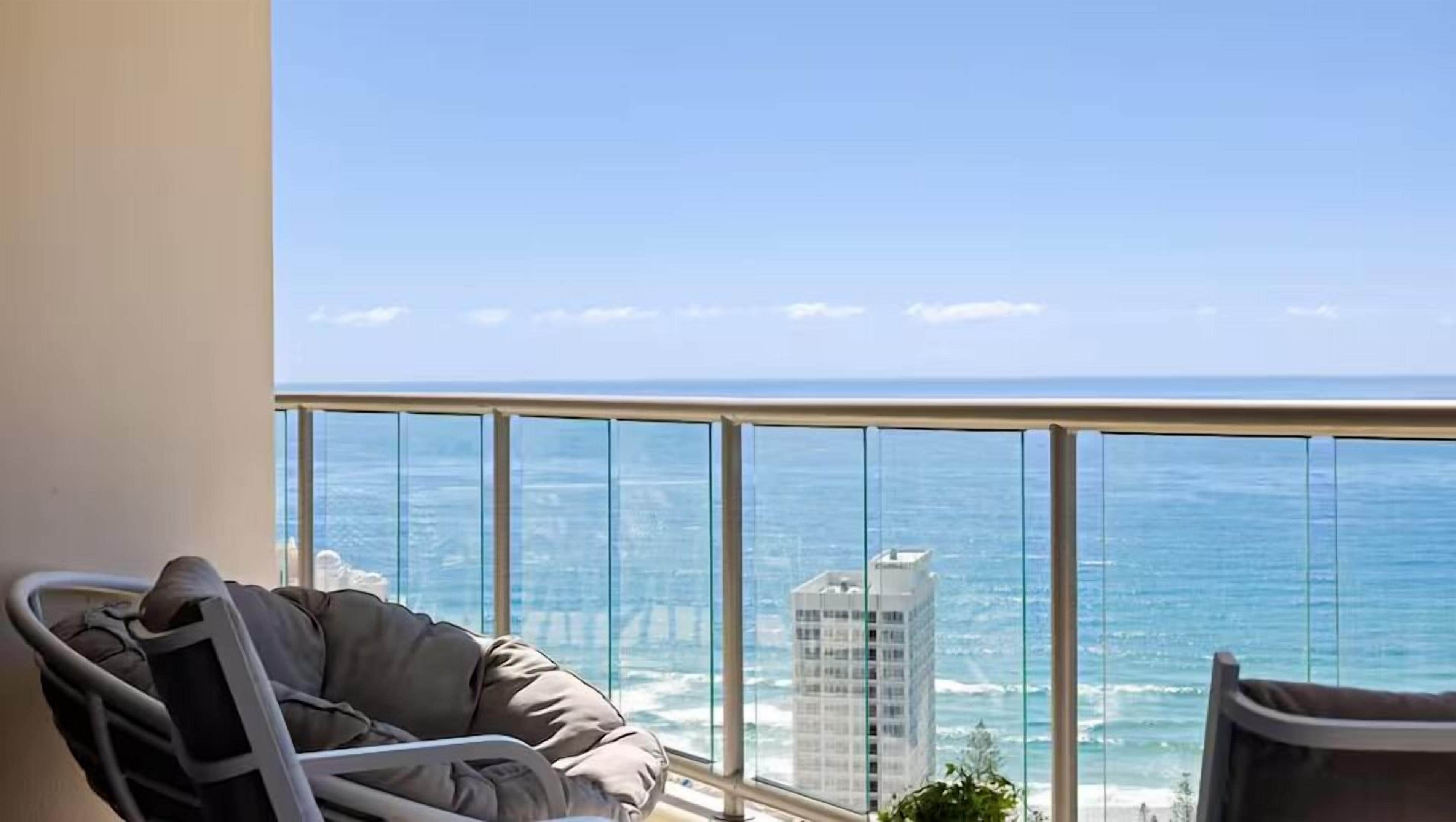 A balcony with a view of the ocean and a building across the water.