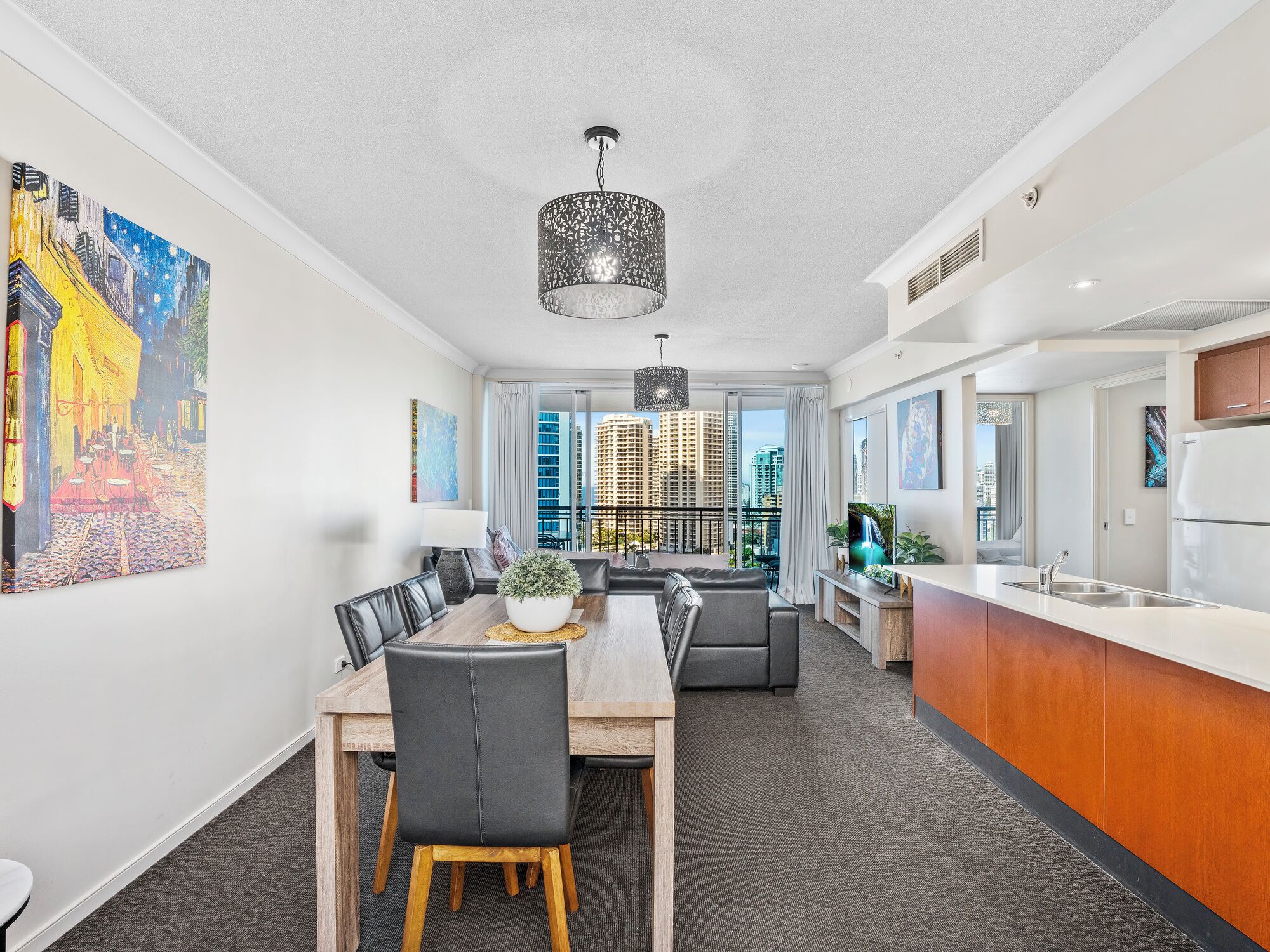 A modern apartment with a dining area, kitchen, and a balcony with city views.