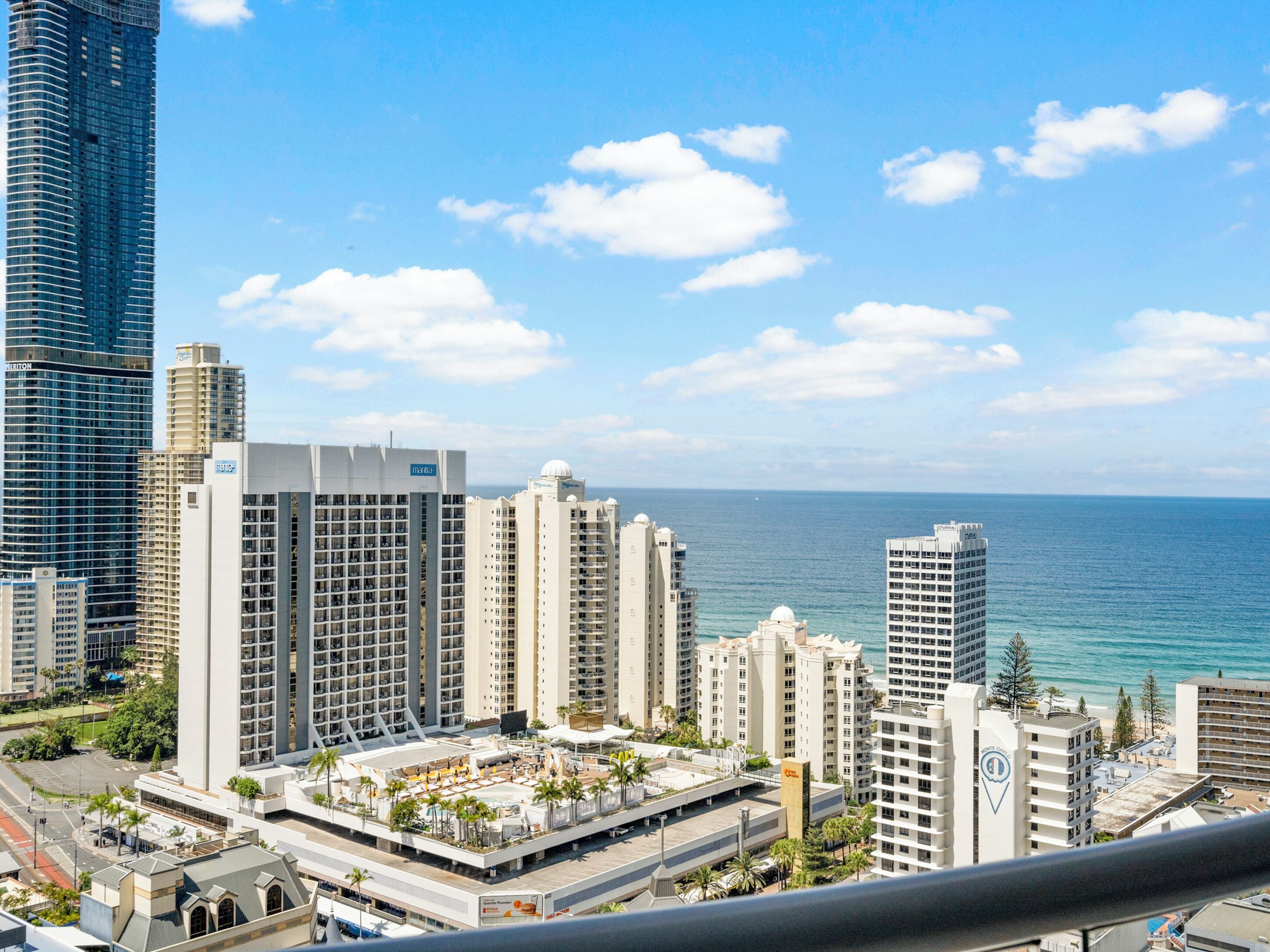 Un hotel di grandi dimensioni con numerosi piani, una piscina sul tetto e vista sull'oceano.