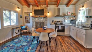 Une cuisine moderne avec des meubles blancs, une cheminée en pierre et un coin repas comprenant une table ronde et des chaises.