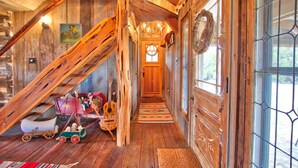 A wooden interior with a staircase, a door with a wreath, and a window with a view. - Log Cabin at Old Glory Ranch | Take a trip back in time! (Wimberley)