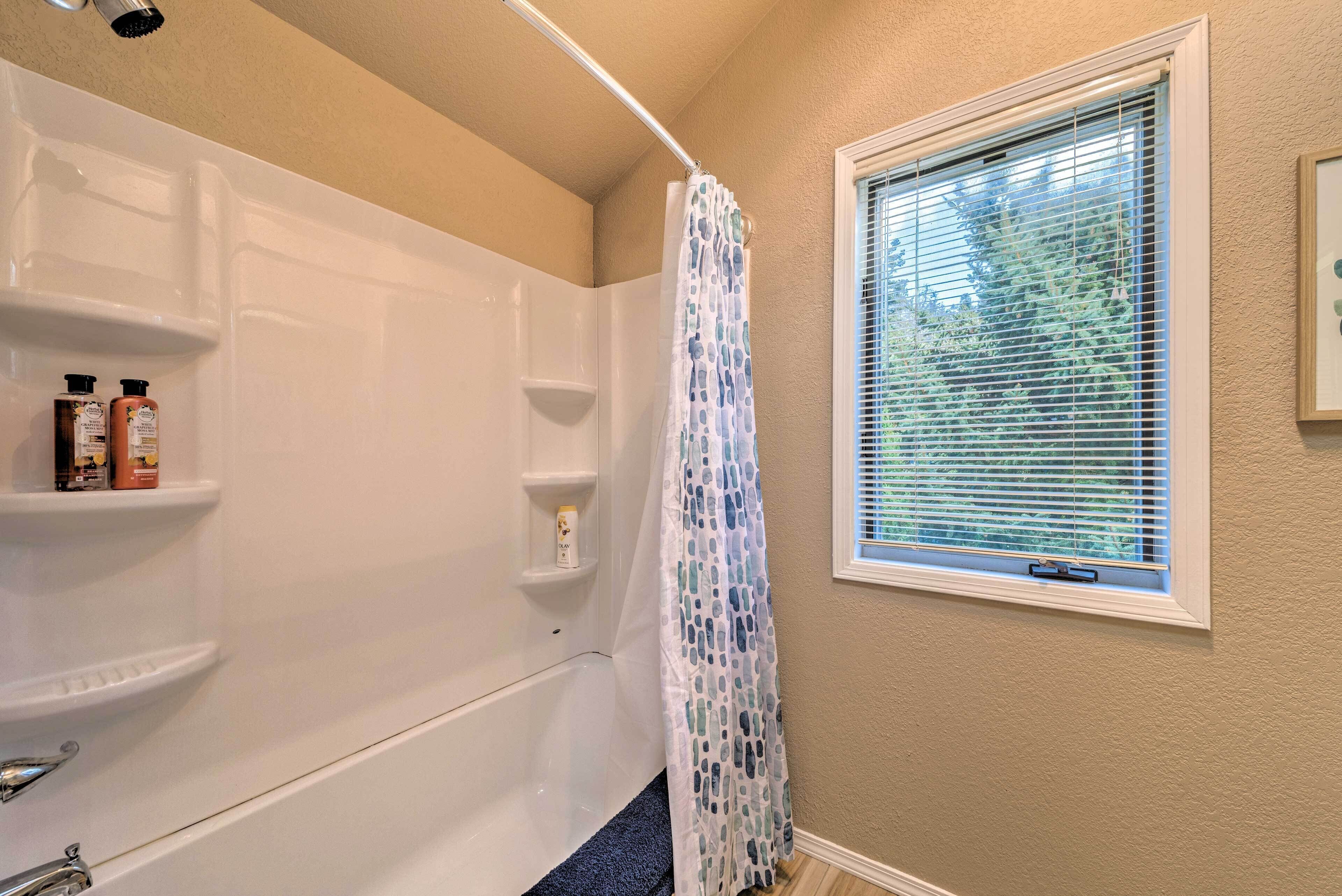 A bathroom with a bathtub, shower curtain, and a window with blinds.