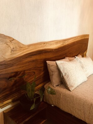 Cozy retreat with a curved headboard, plush bedding, and a touch of greenery.