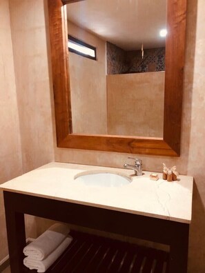 Bathroom features a large mirror, sink, and toiletries on a vanity.