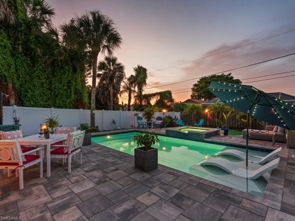 Un jardin avec une piscine, des meubles de patio et un espace salon abrité.