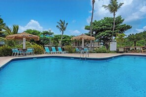 Relax by the pool surrounded by lush greenery and palm trees.