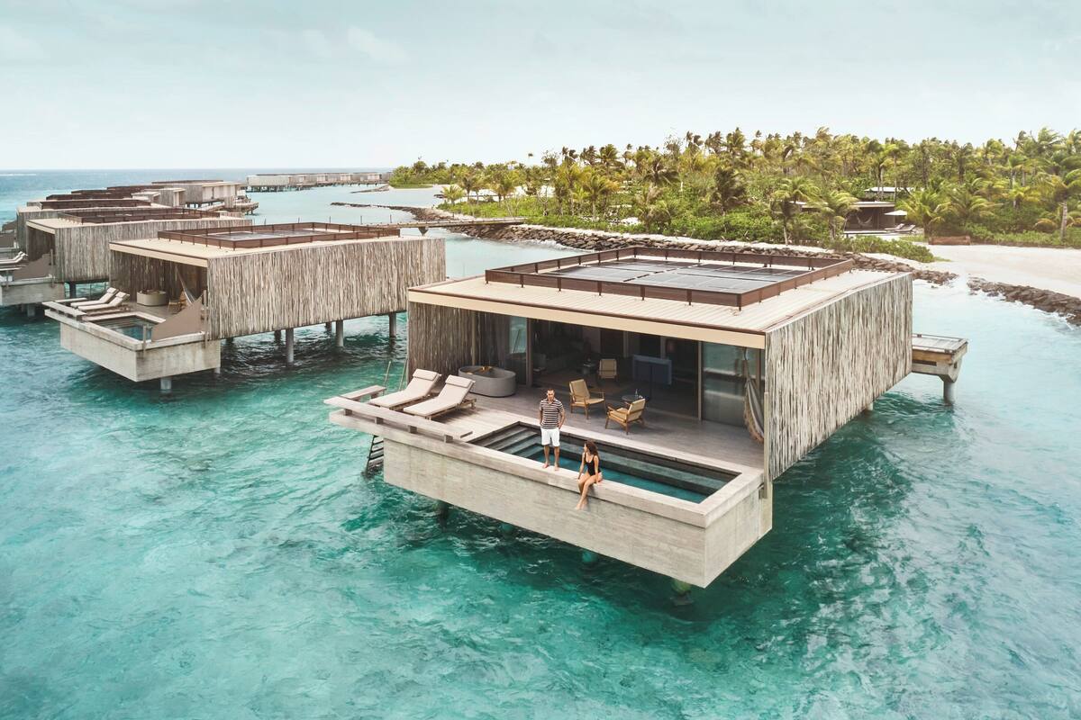Une villa flottante dotée d’une piscine, de chaises longues et d’un espace repas.