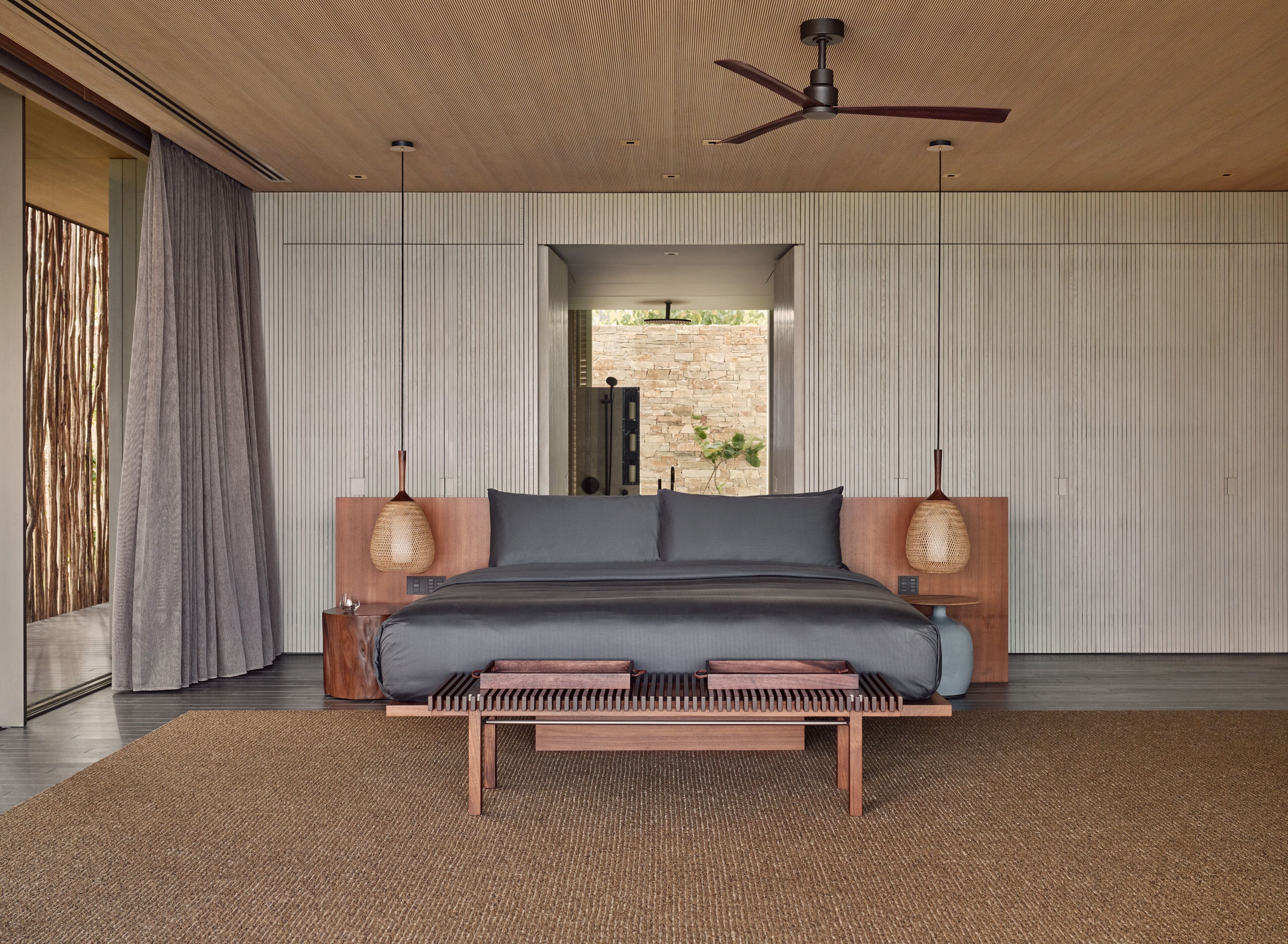 A modern bedroom with a large bed, wooden headboard, and a ceiling fan.