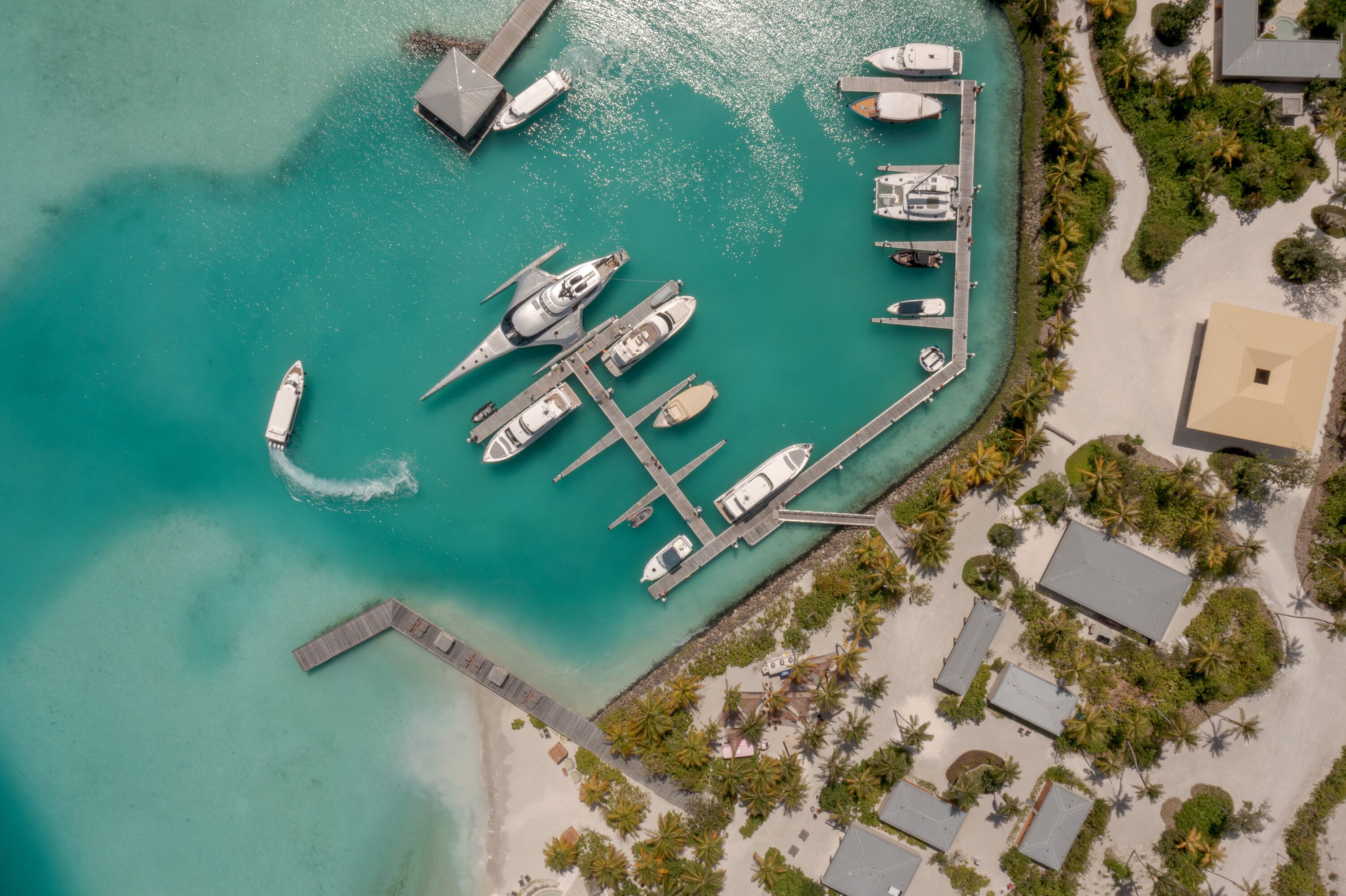 An aerial view of a marina with boats docked, a pier, and surrounding greenery.