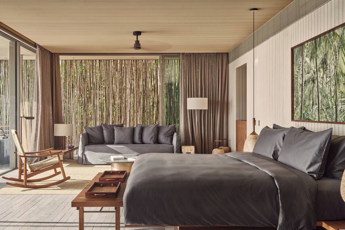 Une chambre à coucher moderne avec un grand lit, un canapé, un fauteuil à bascule et une table basse.