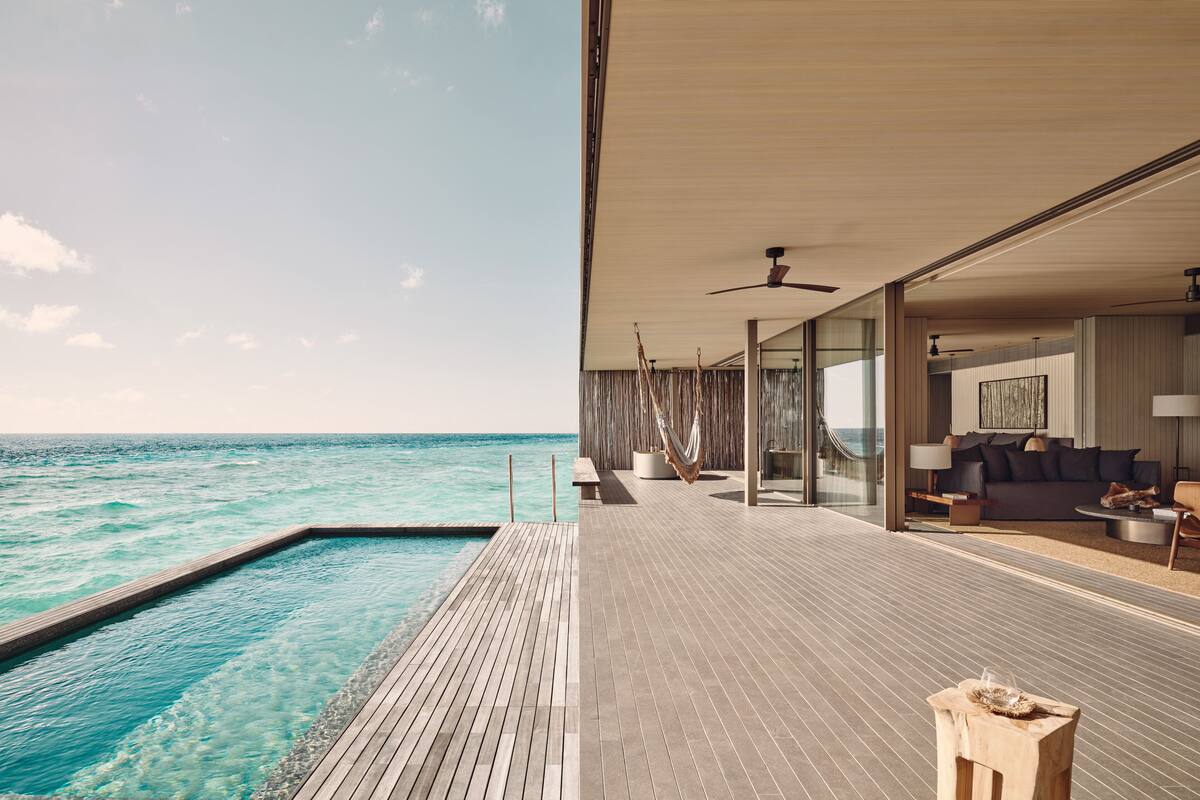 Un espace de vie extérieur moderne, doté d’une piscine, de coins salon et offrant une vue sur l’océan.