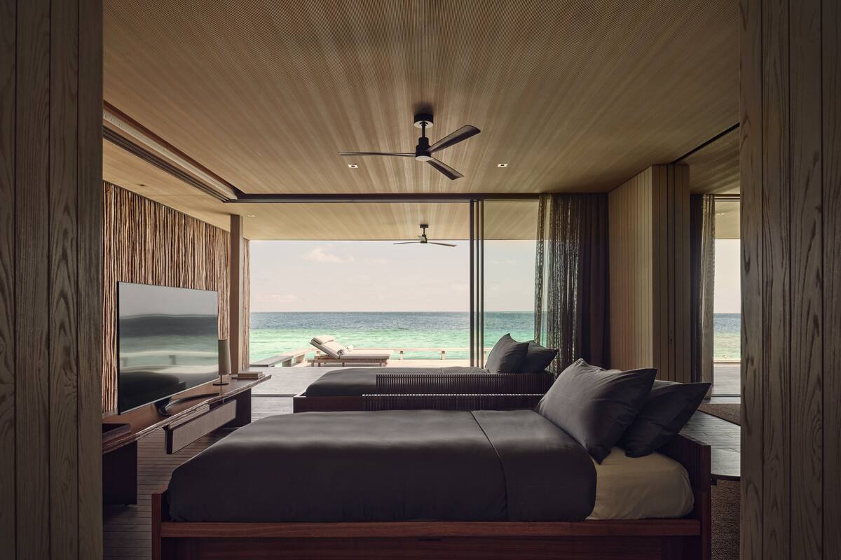 Une chambre moderne avec un grand lit, une télévision et une vue sur l’océan.
