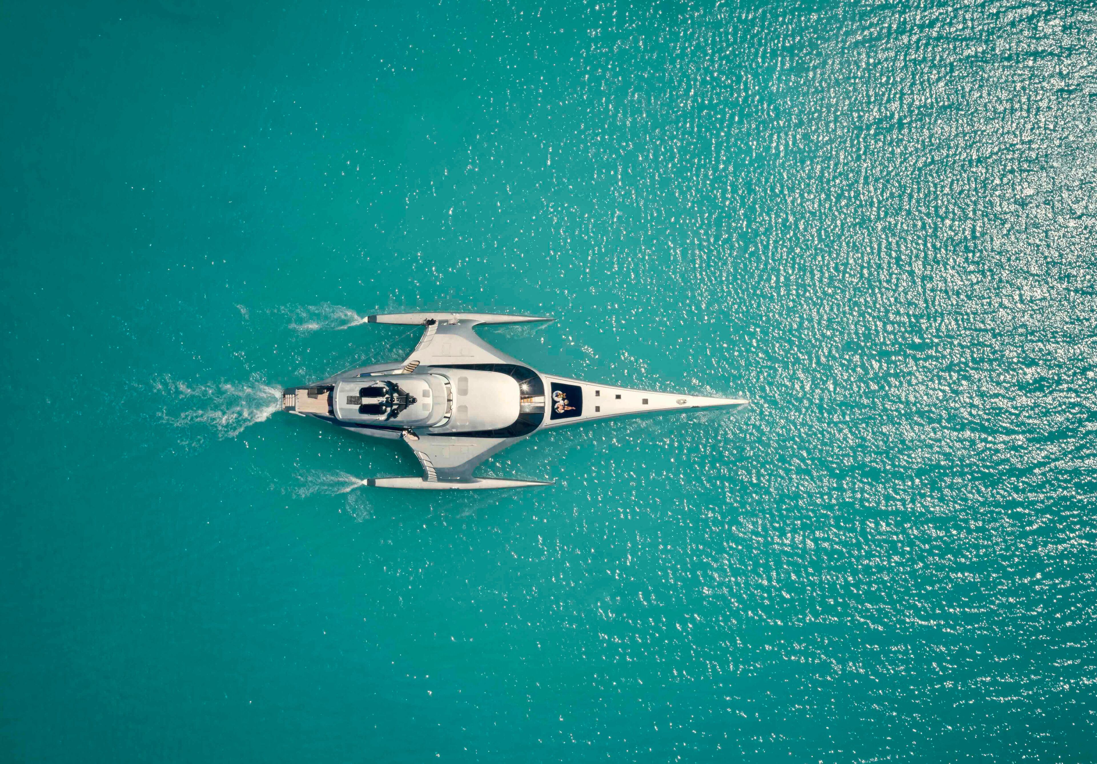 An aerial view of a yacht on turquoise water.