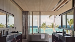 A modern bathroom with a freestanding bathtub, a large mirror, and a view of the ocean. - Patina Maldives, Fari Islands (Fari Islands)