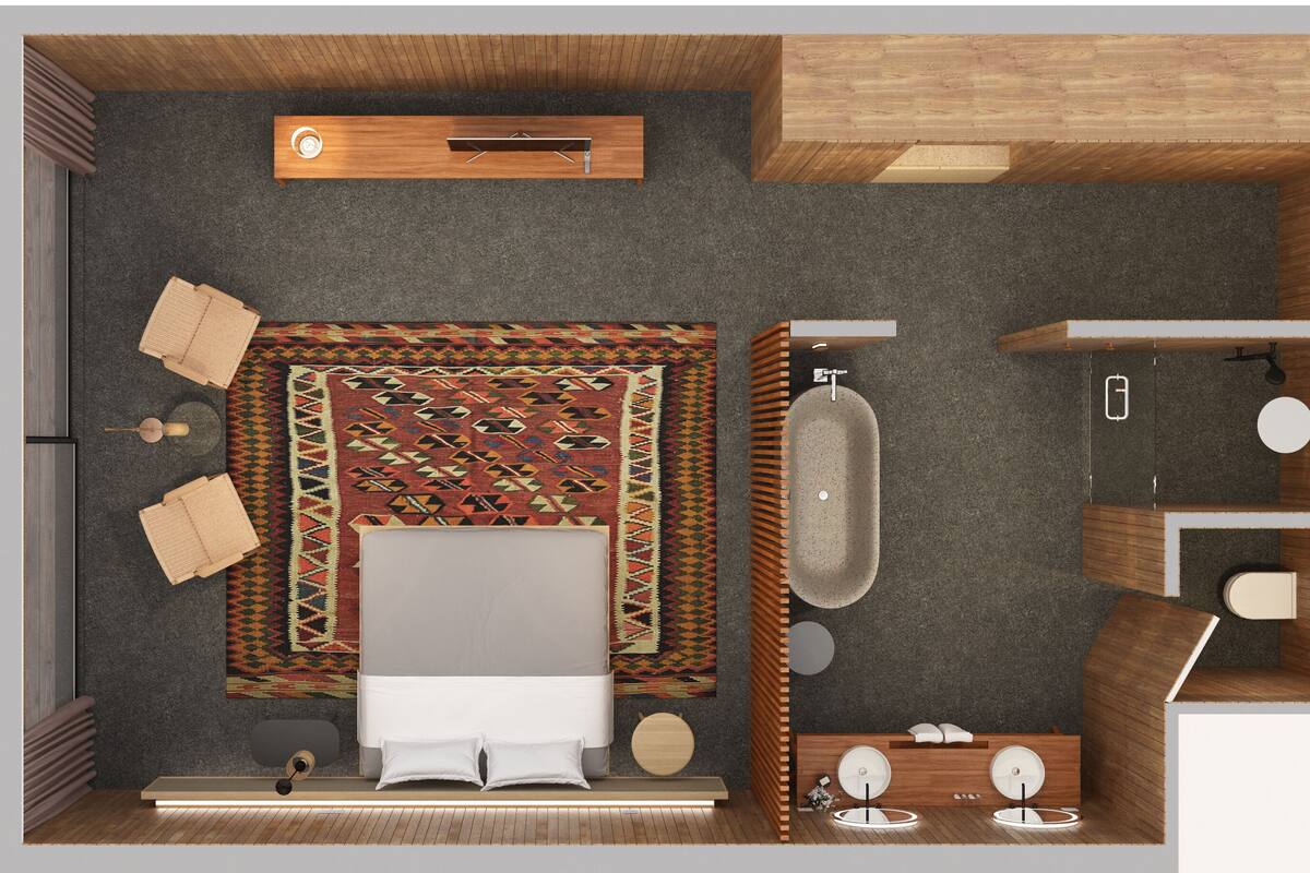 Une chambre d’hôtel de taille modeste, comprenant un lit, une petite salle de bain avec un lavabo et des toilettes, un plafond en bois et un tapis à motifs.