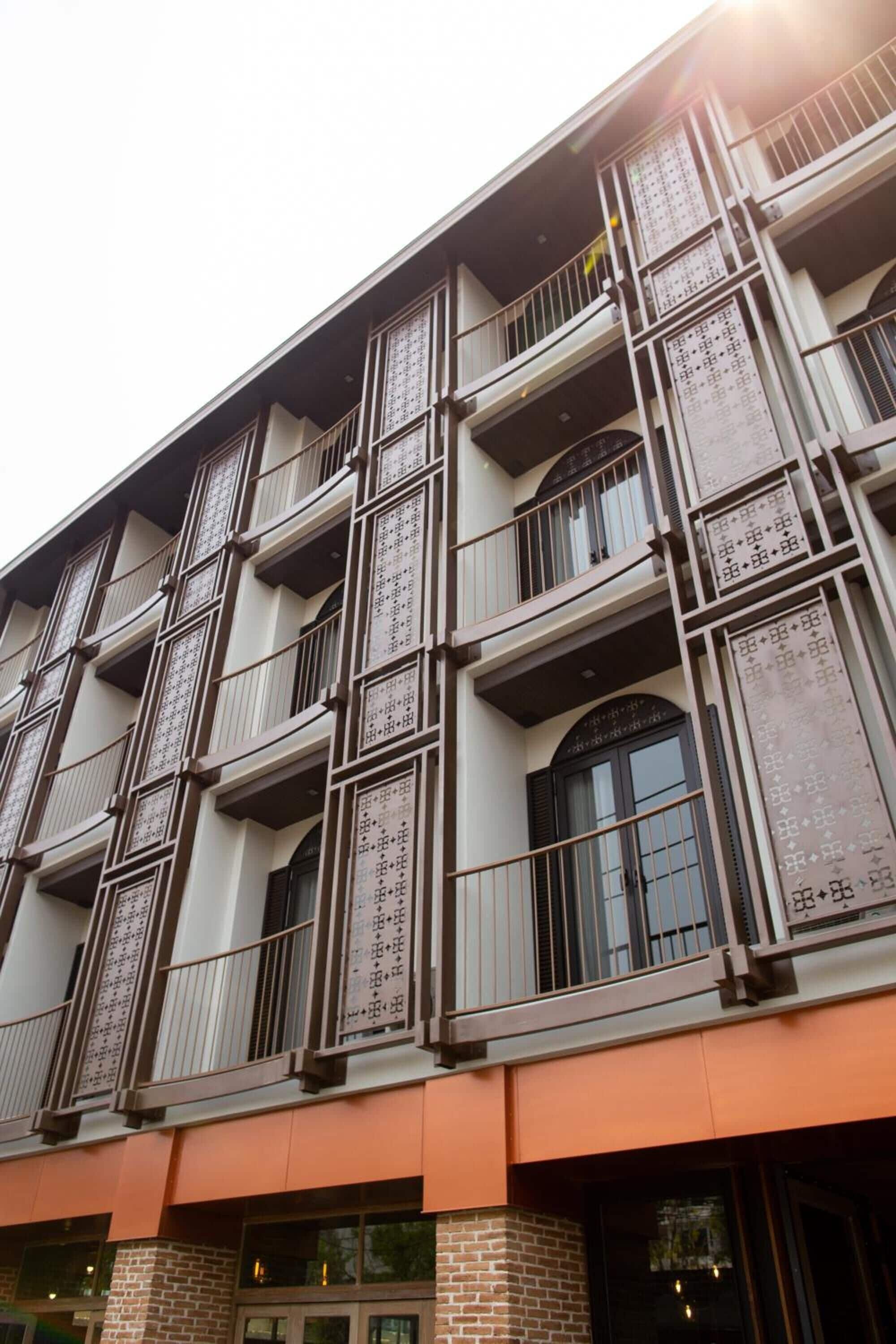 Un immeuble à plusieurs étages doté d’une architecture moderne, avec des balcons pourvus de garde-corps en métal et de grandes fenêtres.