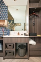 A modern bathroom with a wooden vanity, a mirror, a hanging shower, and a basket under the counter.
