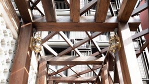 Un couloir doté d’un sol à motifs, de poutres en bois et d’une porte au fond.