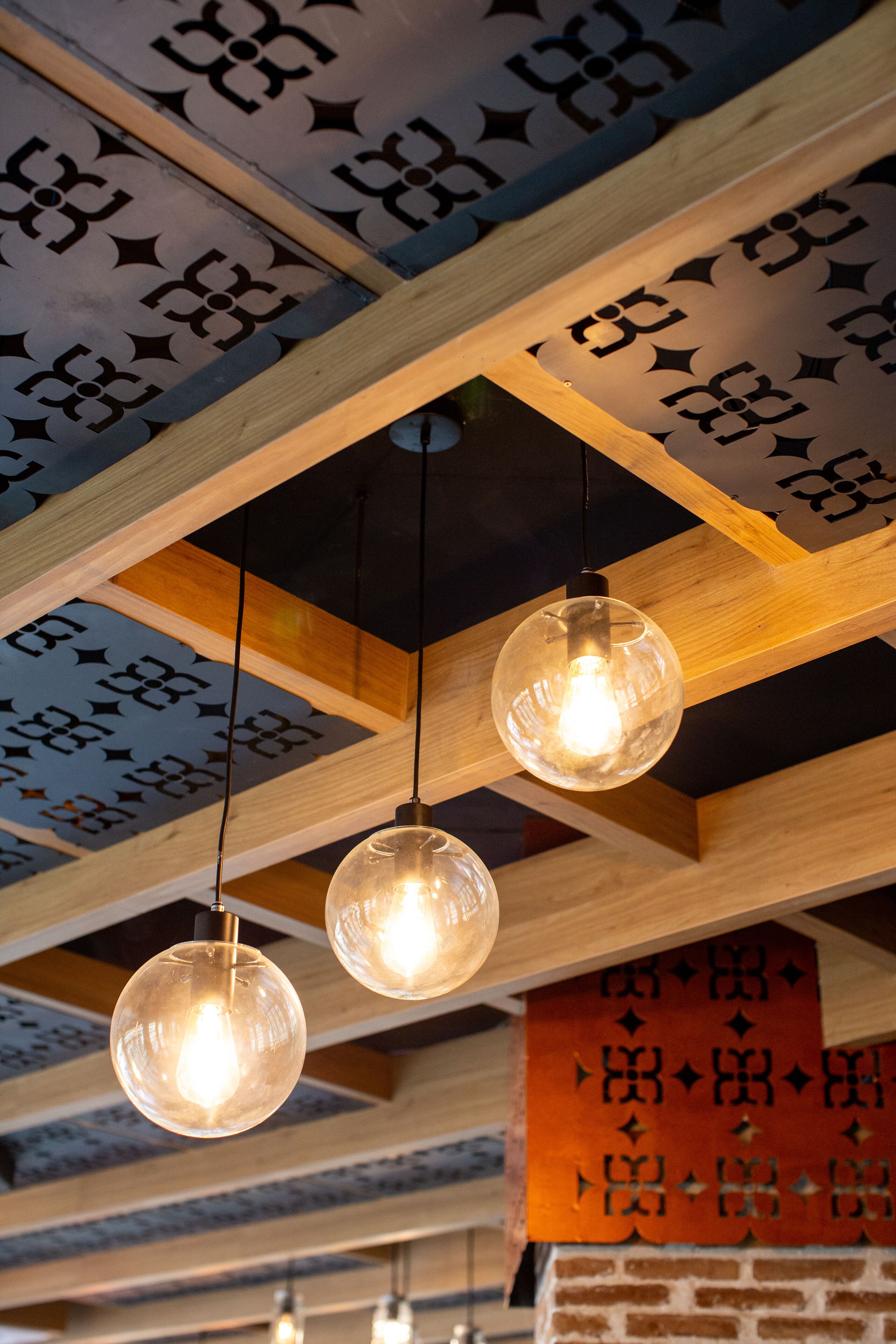 A ceiling with wooden beams and hanging spherical light fixtures.