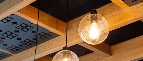 A ceiling with wooden beams and hanging spherical light fixtures.