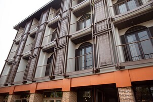 A multi-story building with a brick facade, large windows with metal railings, and a flat roof.