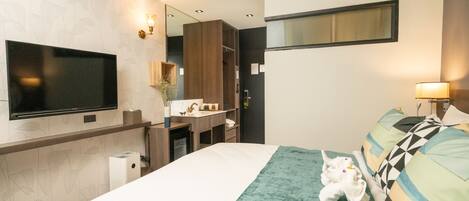 A modern hotel room with a large bed, a flat-screen TV, a mirror, and a bathroom area with a sink and mirror.