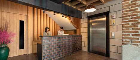 A reception area with a wooden reception desk, a staircase, and an elevator.