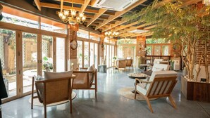 Un espace intérieur spacieux, doté de meubles en bois, de grandes fenêtres et d’un ventilateur de plafond.
