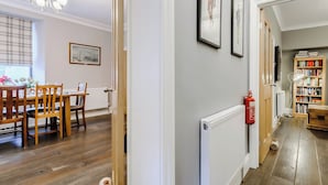 Un coin repas avec une table et des chaises en bois, un lustre et un tableau encadré au mur.