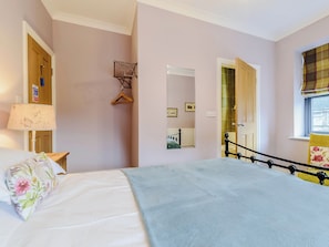 A bedroom with a bed, a hanging chair, a mirror, and a window with curtains.