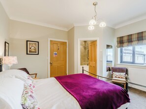 A bedroom with a bed, a wooden door, a window with a view, and a shower area.