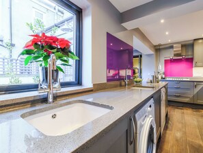 A modern kitchen with a built-in dishwasher, a sink, and a window with a potted plant.