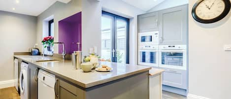 A modern kitchen with a central island, built-in appliances, and a large window.
