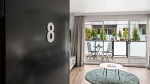 Une chambre moderne dotée d’une grande fenêtre, d’un balcon avec mobilier d’extérieur et d’une table ronde.
