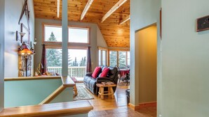 A cozy living area with a wooden ceiling, a black leather sofa, and a dining table with chairs. - Rock Pond Condo 79 | Saddleback, Ski-in/out (Sandy River Plantation)