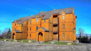 Un immeuble en bois à plusieurs étages, doté de balcons et d’une allée gravillonnée.