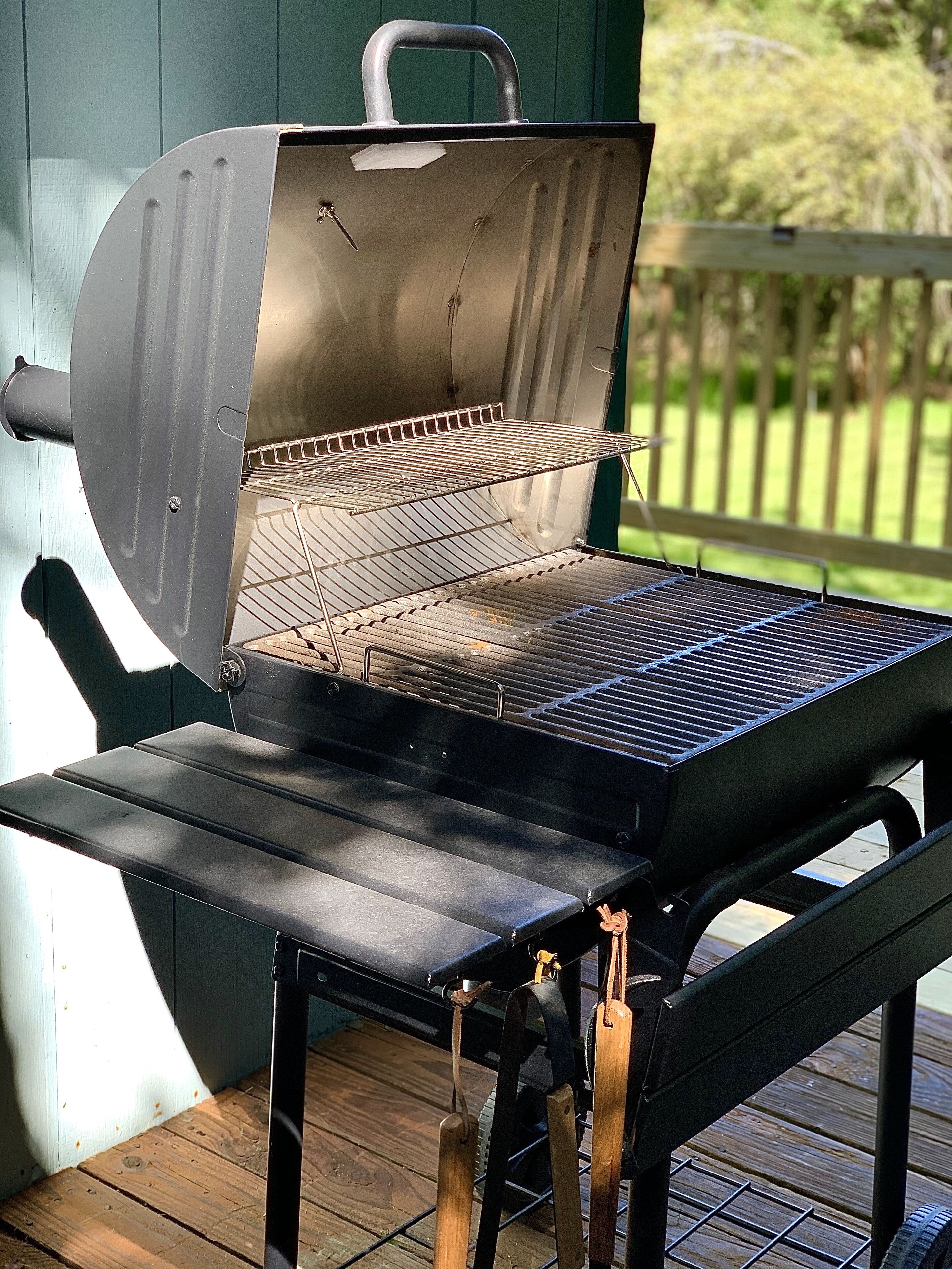 Een kolengrill met een metalen rooster, handvat en deksel.