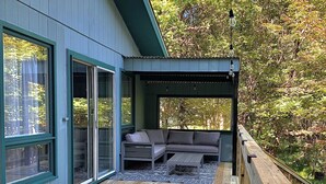 A deck with a wooden floor, a built-in seating area, and a covered section with string lights.