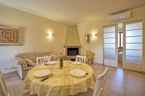 A dining area with a table set for four, a sofa, a fireplace, and a door leading to a balcony.