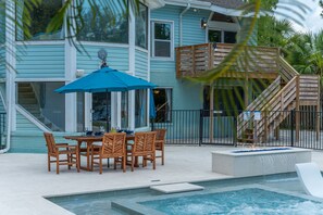 Un espace piscine avec une table et des chaises, un parasol bleu et un escalier en bois.