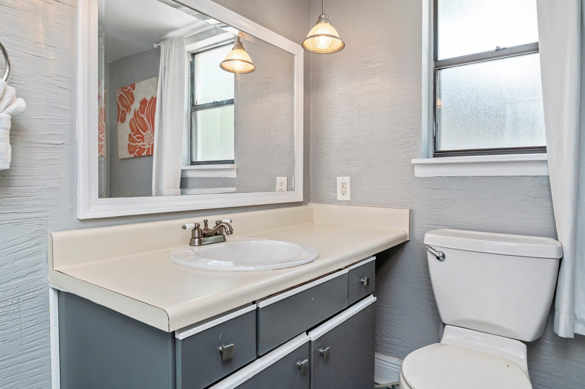 A bathroom with a white sink, a large mirror, and a toilet.