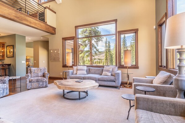 A spacious living room with a large window, a sofa, a coffee table, and a fireplace.