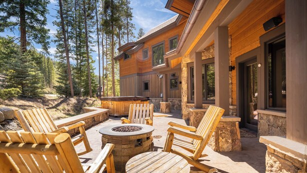 A wooden deck with outdoor seating, stone pillars, and a fire pit. - 555 Independence Road by Summit County Mountain Retreats (Keystone)