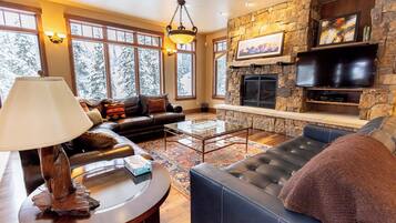 A cozy living room with a stone fireplace, leather sofas, and a large TV.