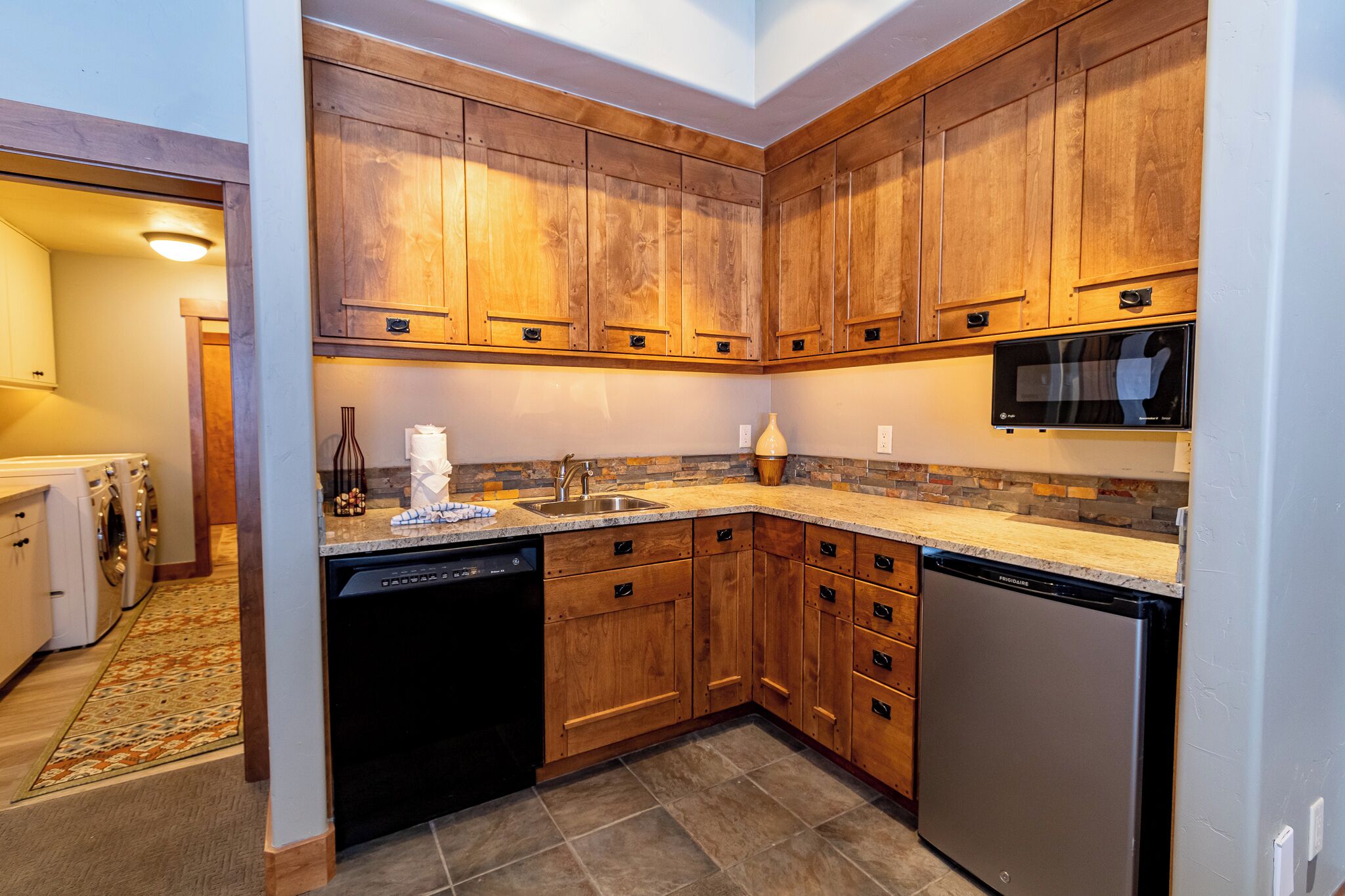 A kitchen with wooden cabinets, a dishwasher, a refrigerator, and a microwave.